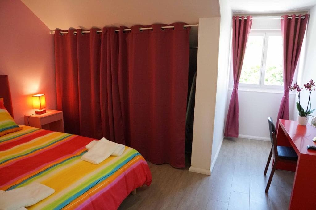 Chambre avec deux lits simples, tons rouges, lumière naturelle