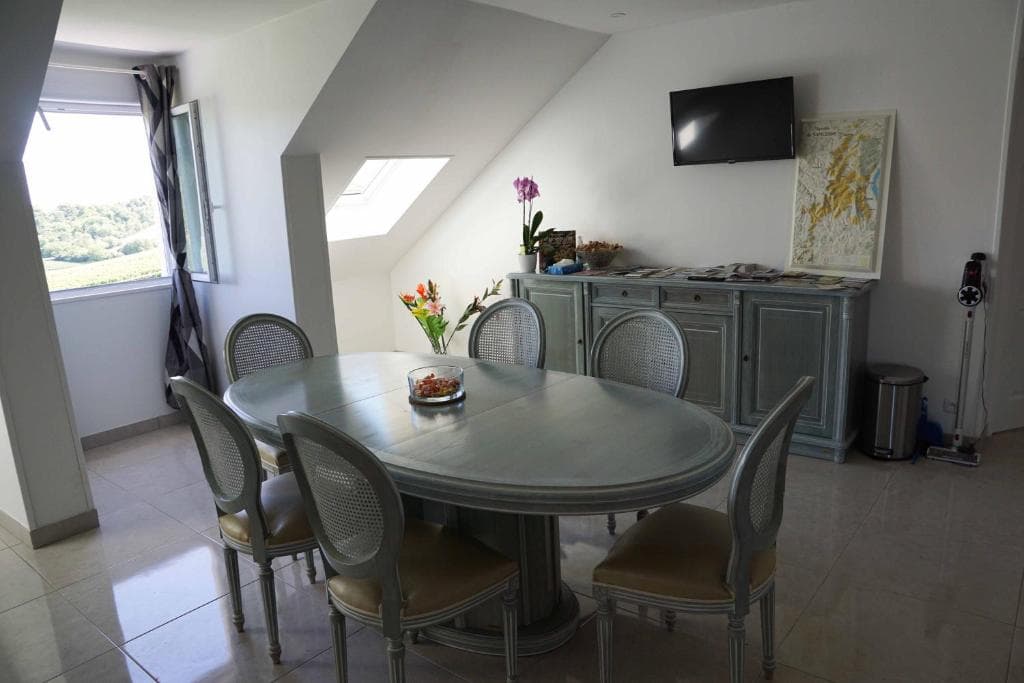 Salle à manger avec table ovale, vue sur les vignes et carte du vignoble